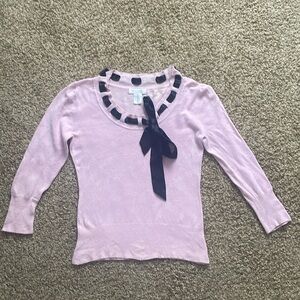 Pink sweater with black tie along neckline